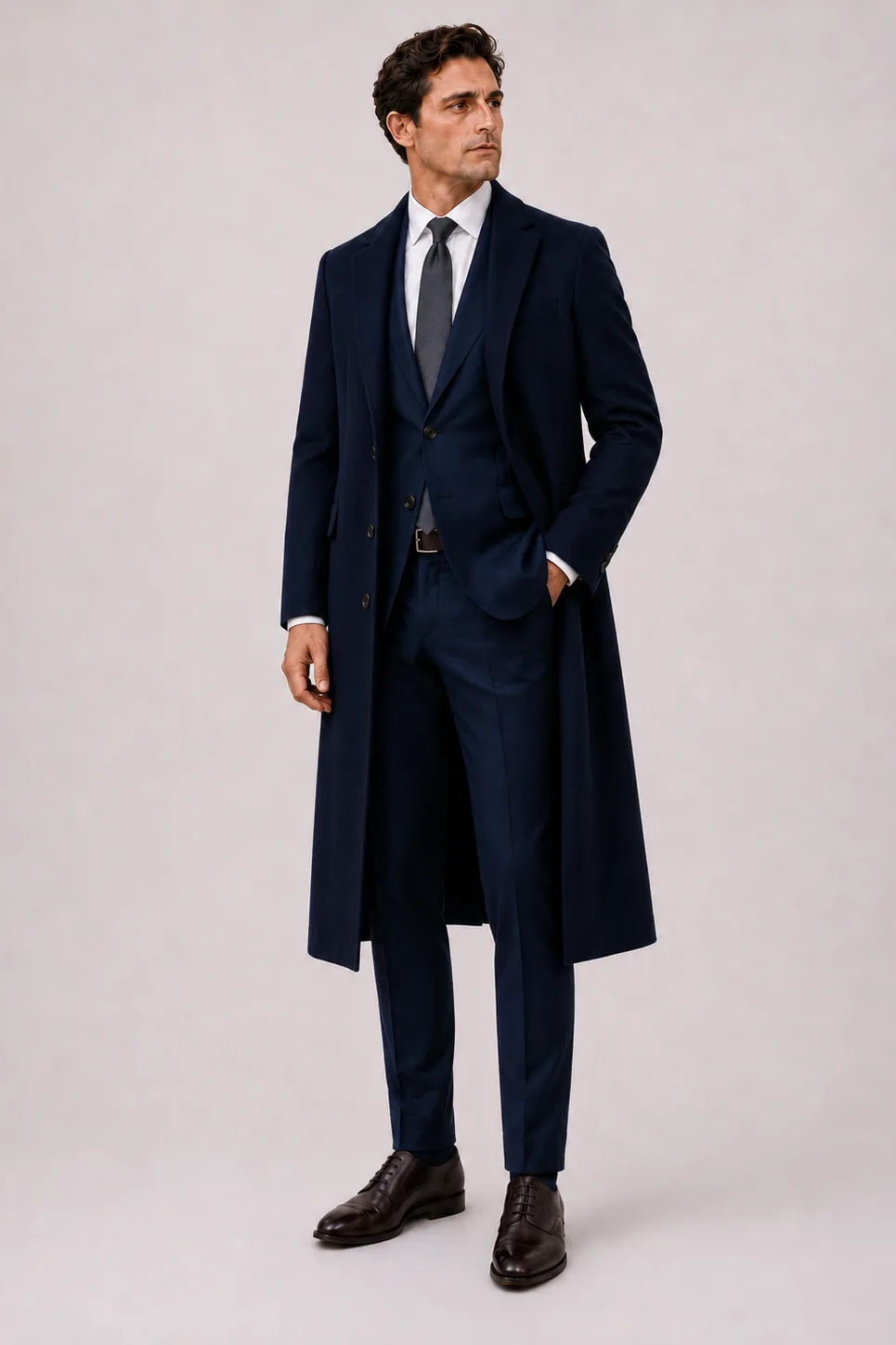 Langer Mantel Navy über Sakko Navy und Business-Hemd Weiss, dazu Anzughose Wolle Navy und Derby