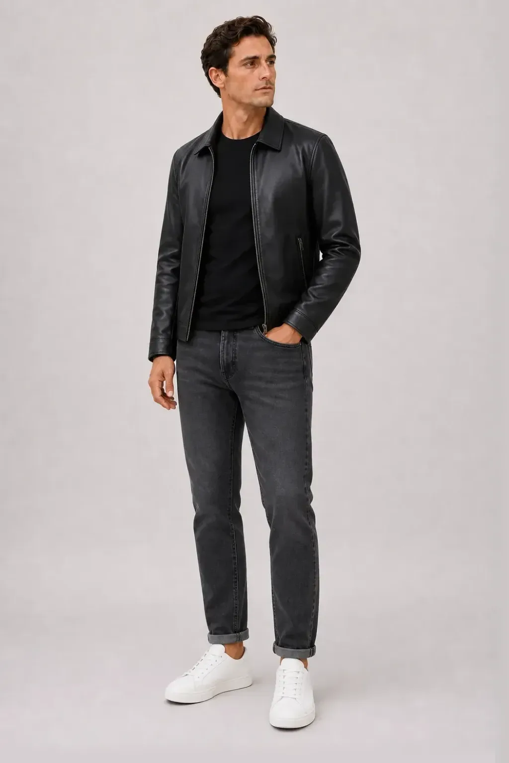 Lederjacke Schwarz über T-Shirt Schwarz, dazu Jeans Dunkelgrau und Sneaker